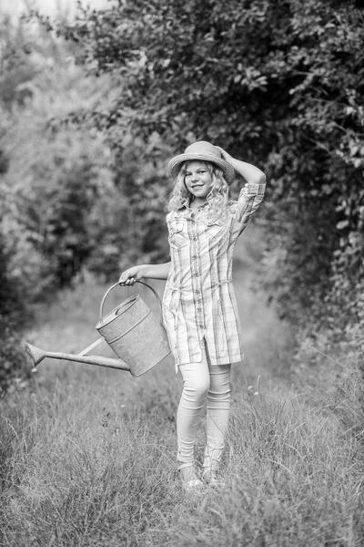 Полив растений в саду. Поливочные инструменты. Девочка держит лейку. Весенний контрольный список садоводства. Улучшение времени орошения. Оптимизировать использование воды. Измерение температуры и солености почвенной воды — стоковое фото