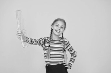Sadece sarışın için değil. Mutlu çocuk mavi taraklı sarı arka planda kalsın. Plastik saç tarağıyla gülümseyen küçük kız. Küçük çocuk uzun saçlarını tarıyor. Güzellik salonu. Kuaförlük. Saç şekillendirme