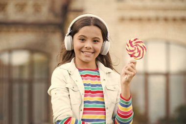 Tatlı şeker mikrofonu söyleyen mutlu çocuk. Mutlu çocukluk. Lolipop şekeri tutan çocuk kulaklıklar. Dışarıda şekerli mutlu çocuk eğleniyor. Kalori ve enerji. Liseli kız tatlıyı hak ediyor. Tatlı remix