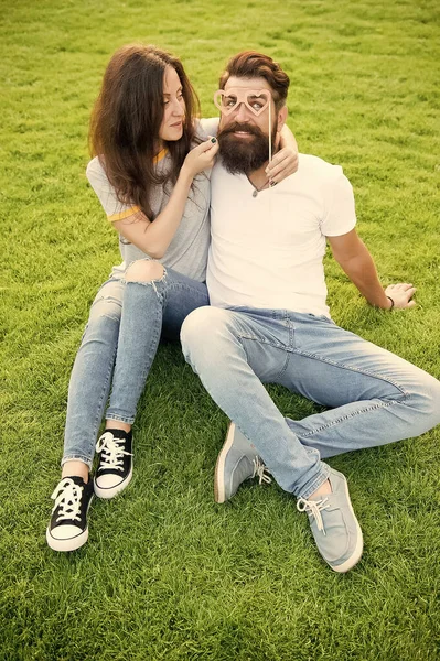 Perfect pair for perfect couple. Couple in love having fun with prop glasses. Couple of bearded man and sexy woman on green grass. Family couple relaxing on summer day