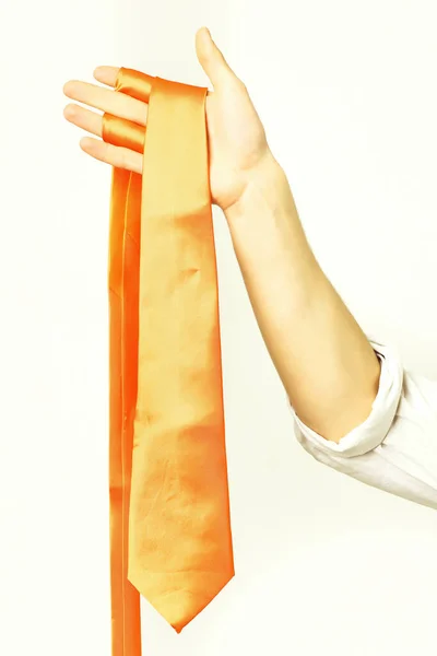 Strong male hand holding orange tie isolated on white background — Stock Photo, Image