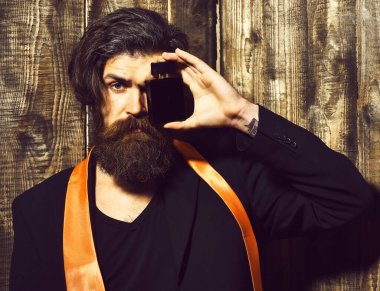 Takım elbiseli beyaz hippi parfüm tutuyor.