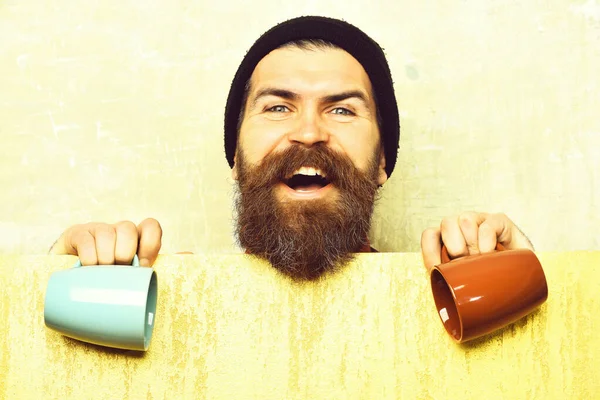 Barbudo brutal hipster caucásico con hoja de papel y tazas —  Fotos de Stock