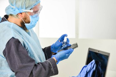 Evdeki Sosyal Medya Etkisi. Coronavirus salgını hakkında bilgi toplayın. Kendini karantinaya almış bir adam. Koruyucu maskeyle evde kal. Dezenfektan jeliyle ellerini temizliyor. virüslerden uzak dur