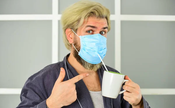 Serious about hygiene. Cover mouth and nose with mask and make sure no gaps between face and mask. Totally protected. Wearing mask protect from coronavirus. Guy in mask drink tea coffee using straw