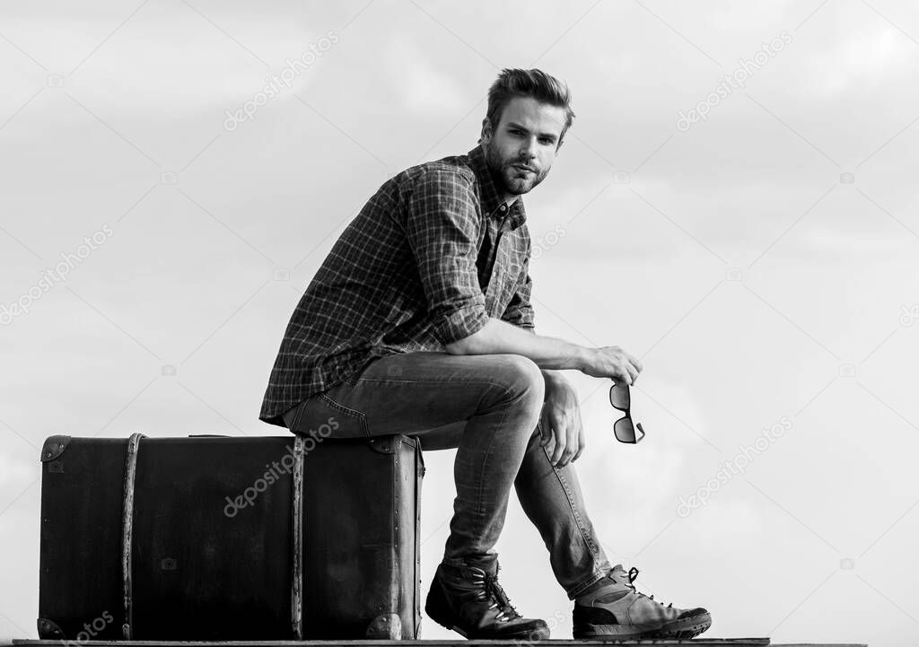 Business trip. Handsome guy traveler. Guy outdoors with vintage suitcase. Luggage concept. Travel with luggage. Travel blogger. Vacation time. Travel agency. Man sit on suitcase before journey