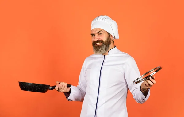 Gezond ontbijt. Man met koksmutsen op keuken. Koken voedsel concept. Braadpan vasthouden. beste kwaliteit. baardkok in uniform met gereedschap. Een man met een baard houdt een kookpan vast. bereiden van voedsel in de keuken — Stockfoto