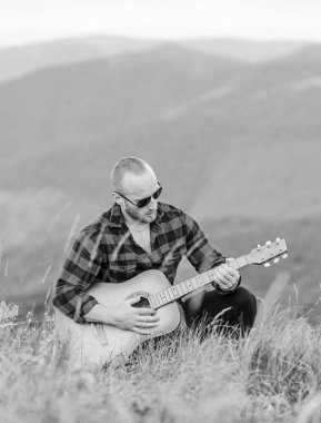 Müzik beni sadece güçlendirir. Hipster modası. Batı kampı ve yürüyüş. Mutlu ve özgür. Akustik gitaristli kovboy adam. Country müzik şarkısı. Kareli gömlekli, gitarlı seksi adam.