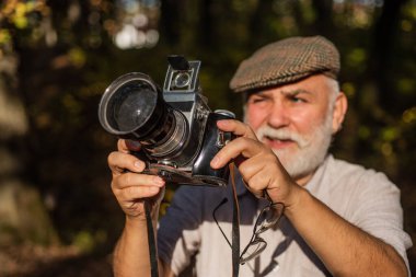 Kuşları izlemeyi seviyor. Mükemmel bir çerçeve. Eski fotoğrafçı çekim yapıyor. Elle ayarlar. Emeklilik hobisi. Deneyimli fotoğrafçı. Klasik kamera. Yaşlı adam doğayı vurdu. Profesyonel fotoğrafçı.