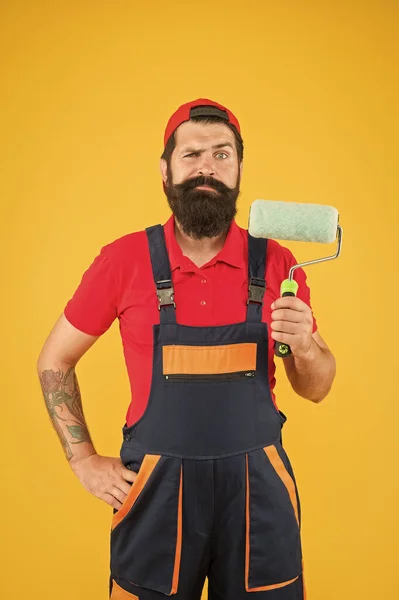 Ремонт дома. Hipster builder in cap yellow background. ассистент монтажника в рабочей форме. инженер-конструктор готов покрасить стену. концепция ремонта. бородатый человек работник с роликовым инструментом — стоковое фото