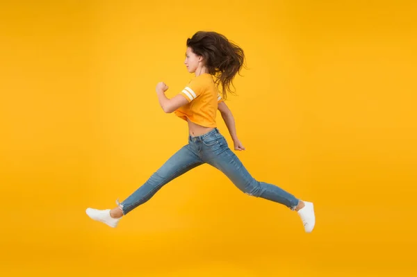 Przypływ energii. Energiczna dziewczyna w żółtym tle. Seksowna kobieta w energicznym ruchu. Porusza się w pośpiechu w energetycznym nastroju. Zwyczajny styl mody. Młoda i energiczna. Szybki, ale pełen wdzięku. — Zdjęcie stockowe