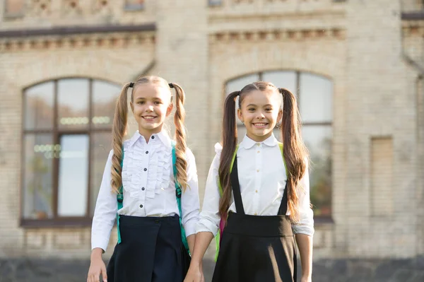 Fortunato a conoscersi. Allegre studentesse intelligenti. Scolarette felici all'aperto. Le piccole studentesse indossano l'uniforme scolastica. Studentesse carine con lunghe code di cavallo che sembrano affascinanti. Fine dell'anno scolastico — Foto Stock