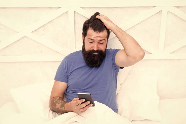 Checking phone first thing in morning. Bearded man use mobile phone in bed. Staying mobile with cell phone. Personal communication. Good morning. Waking up. Phone for keeping in touch