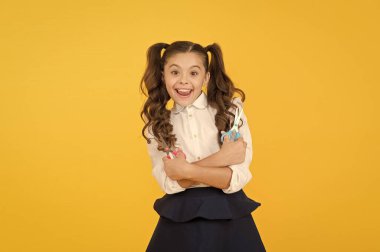 Çocuk deli gibi kesilmeye hazır. Sarı arka planda elinde makas tutan mutlu küçük çocuk. Resmi okul üniformasıyla gülümseyen küçük bir çocuk. Sanat derslerinde öğrenen neşeli kadın çocuk.