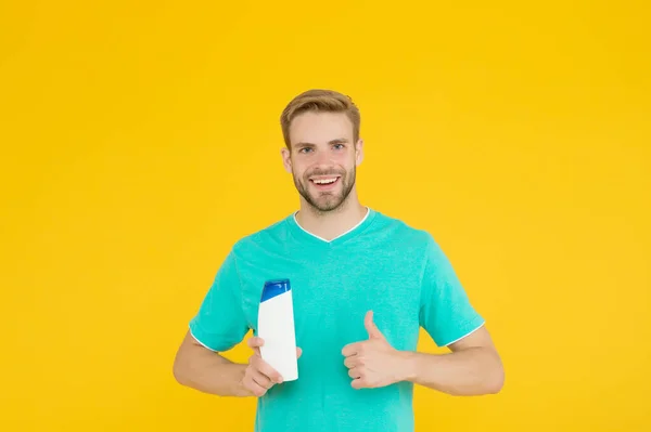 Buena elección. Un hombre guapo sostiene la botella de champú. El hombre barbudo sostiene el producto cosmético. Peluquería arreglando. Peluquería profesional. Cosméticos para el cuidado del cuerpo para baño o ducha. Cuidado del cabello. Cosmética masculina —  Fotos de Stock