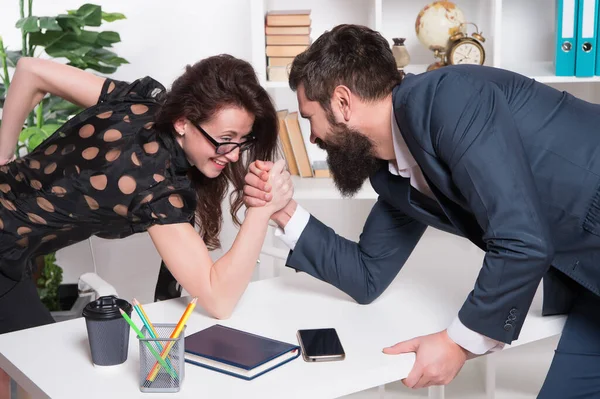 Whos stronger. Bearded man and sexy woman arm wrestle in office. Workplace relationship. Competitive relationship. Relationship between business partners. Professional couple. Relationship or rivalry