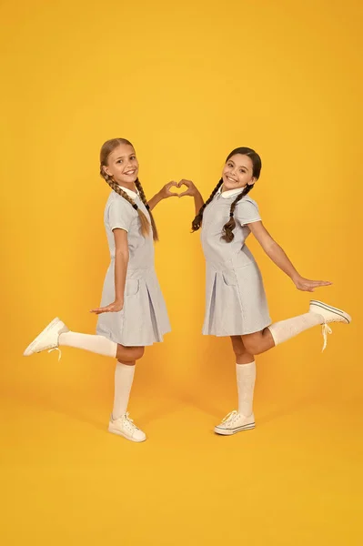 Sisterhood love. children in vintage style. old school. happy friends on yellow background. kid fashion. childhood happiness. small girl in school uniform with retro look. friendship and love concept — Stock Photo, Image