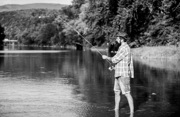 Pesca de caza mayor. relajarse en la naturaleza. hombre barbudo maduro con pescado en caña. pescador exitoso en el agua del lago. pesca hipster con cuchara-cebo. pasatiempo peces mosca. Actividad de verano. Es un pez grande. — Foto de Stock