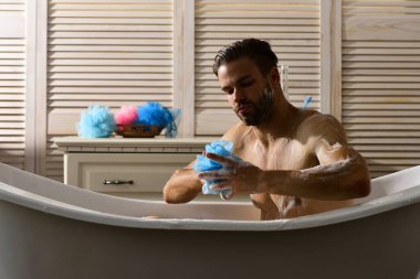 Banyodaki adam arka planda köpükle kaplı.