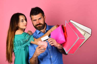 Birbirini seven çiftler alışveriş torbalarını pembe arka planda tutarlar..