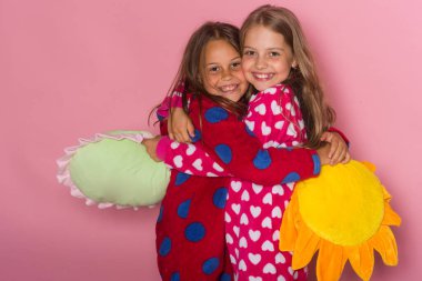 Gülümseyen yüzlü çocuklar sarılır. Benekli pijamalı kızlar.