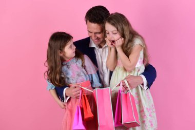 Kardeşler ve babalar hediyelerini paylaşır. Okul kızları ve babaları paketleri tutuyor.