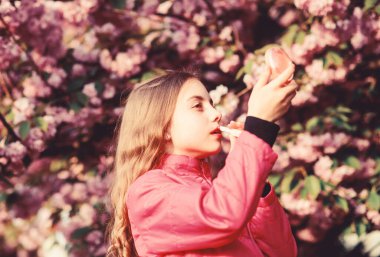 Kiraz çiçekli mutlu kız. Sakura ağacı çiçek açıyor. Cilt bakımı. Cilt için doğal kozmetik. Yaz. Çocukluk. Bahar çiçeğindeki küçük kız çocuğu çiçek açar. Çiçek kokusu, alerji. Güzel bir bahar günü.