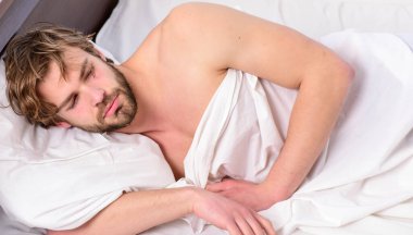 Yakışıklı adam esniyor ve kollarını kaldırıyor. Genç bir adam yatakta uyanıyor ve kollarını açıyor. Genç, yakışıklı adam tamamen dinlenmiş olarak uyanıyor..