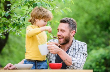 Baba oğul dışarıda yemek yiyorlar. Birlikte vakit geçirmeyi seviyoruz. Vejetaryen diyeti. Sağlıklı yemek ve diyet. Süt ürünleri. Babalar günün kutlu olsun. Babasıyla küçük çocuk mısır gevreği yiyor. Aile yemeği zamanı.