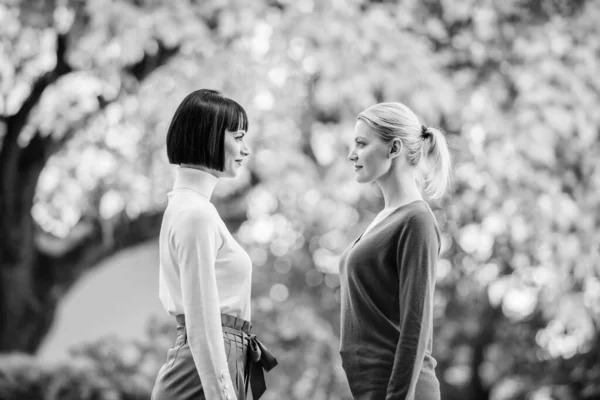 Duas mulheres enfrentam-se uma à outra. meninas olhando nos olhos uns dos outros. amizade feminina. a passear no parque ensolarado. melhores amigos. Encontro casual. A amizade acabou. Retrato de duas mulheres bonitas — Fotografia de Stock