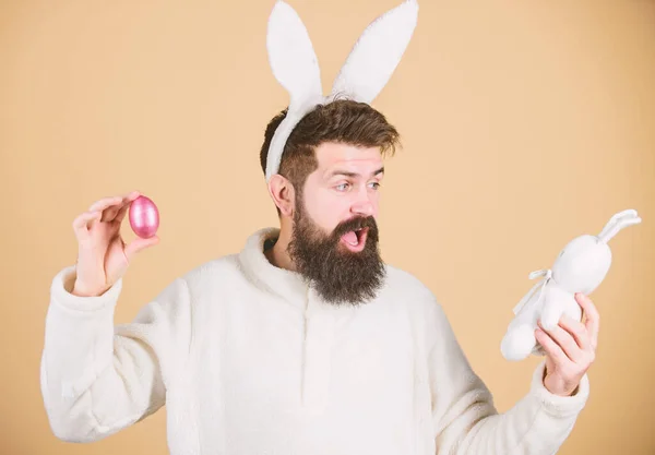 Святкуй Великдень. Хлопець бородатий хіпстер веселий кролик з довгими білими вухами. Великодній кролик. Чоловік у костюмі кролика грає з іграшкою. Смішний кролик м'яких вух. Концепція Великодня. Натюрморти — стокове фото