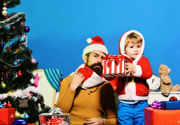 Weihnachtsmann und kleiner Helfer inmitten von Geschenkboxen am Weihnachtsbaum. — Stockfoto