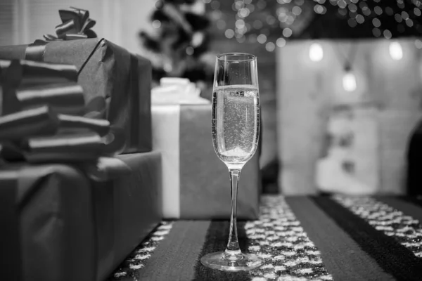 Vier nieuwjaar. Een glas champagne dicht. Traditioneel nieuwjaarskenmerk. Gelukkig nieuwjaar en vrolijk kerstfeest. Champagne elegant glas. Glas gevulde mousserende wijn of champagne in de buurt van geschenkdozen — Stockfoto