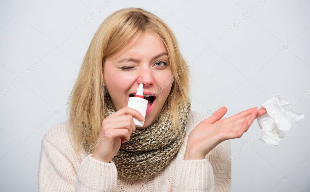 Blocking a nostril. Cute woman nursing nasal cold or allergy. Unhealthy girl with runny nose using nasal spray. Sick woman spraying medication into nose. Treating common cold or allergic rhinitis