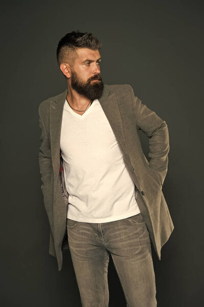 Никто не рождается стильным. Стильный бизнесмен серый фон. Бородатый мужчина с жестоким стильным взглядом. Свободный, но стильный. Мода и тенденции стиля. Бизнес стиль жизни
