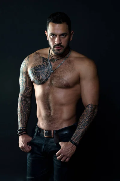 Sport and fitness. Masculinity. Muscular torso. Jewelry for real men. Bearded man with tattooed torso. Macho sexy bare torso. Fit model with tattoo art skin. Sportsman or athlete with beard and hair