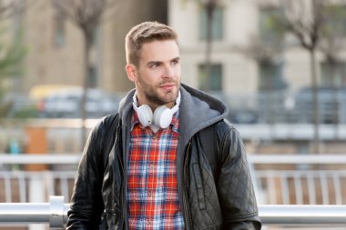 Yayın hizmetleri konsepti. Modern insanların yaşam tarzı. Yakışıklı şık adam, açık havada müzik dinliyor. Adam kulaklıkla müzik dinlemeyi seviyor. Stereo sesi. Ses ve müzik teknolojisi. Müzik deneyimleri