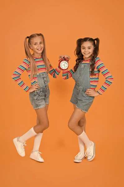 Kleine Kinder lächeln mit mechanischer Uhr. Schuluhr. Timing persönlicher Plan und Zeitplan. Zeitkonzept. Sackgasse. glückliche kleine Mädchen halten Vintage-Wecker auf orangefarbenem Hintergrund — Stockfoto