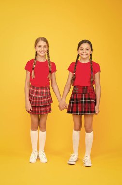 güven konsepti. eğitim konsepti. geri okula. bilgi günü. çocukluk mutluluğu. çocuk moda. Dostluk ve kardeşliği. okul üniforması mutlu kızlar. sarı arka planda akıllı küçük kızlar