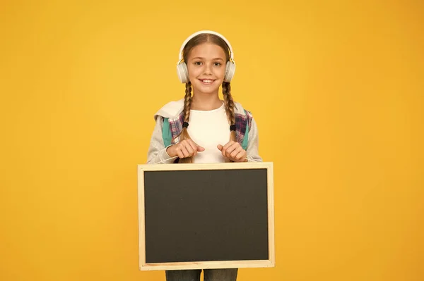 Hipster girl hold blackboard vazio. estudante estilo casual mostrar informações. Compras na escola. música nos auscultadores. projeto de apresentação de crianças. Bem-vindo à nossa escola moderna — Fotografia de Stock