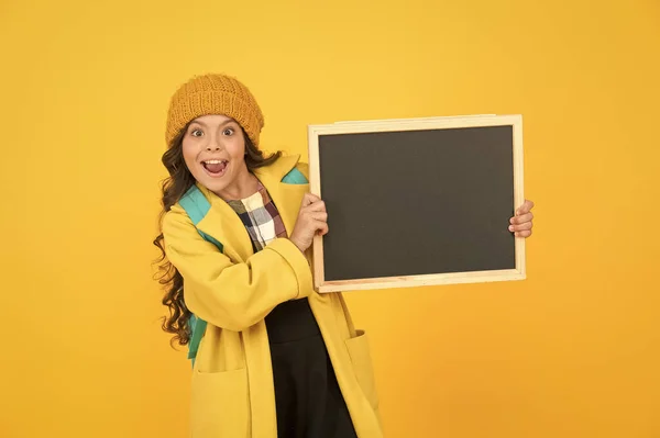 あなたの広告は上に得る。幸せな小さな子供は広告板黄色の背景を保持します。女の子の広告商品やイベント。学校広告、コピースペース — ストック写真