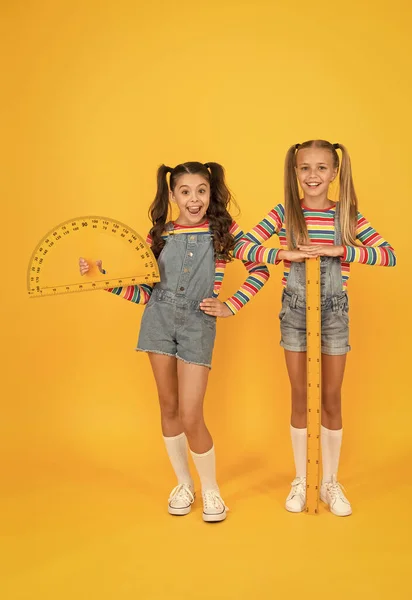 Club scolaire. Des écoliers avec des instruments de mesure. Petite fille prêt leçon de géométrie. Mignonnes écolières tenant rapporteur et règle pour la leçon de l'école. Étudier la mesure. Tâche intéressante — Photo