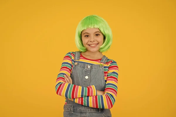 Schönheitswahn. Schönheitslook des kleinen Modells. Glückliche Mädchen tragen grüne Haare Perücke gelben Hintergrund. Mode und Schönheit. Schönheitssalon — Stockfoto