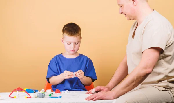 Medische verzekering. Eerste hulp. Geneeskunde concept. Kid kleine arts zitten tabel medische hulpmiddelen. Gezondheidszorg. Medisch onderzoek. Jongen schattig kind en zijn vader arts. Ziekenhuismedewerker. Medische hulp — Stockfoto