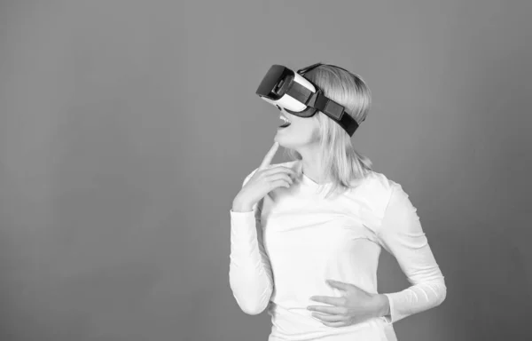 Egy nő virtuális valóság fülhallgatóval. Boldog fiatal nő visel virtuális valóság szemüveg néz filmeket, vagy játszik videojátékok. Csinos nő játszik játék virtuális valóság szemüveg. — Stock Fotó