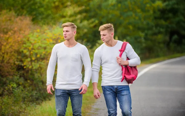 Dva bratři jdou na dobrodružství. koncepce přátelství. muži stopovali. muž ležérní styl cestování s batohem. Pěší turistika na dálnici. na cestě domů. Budoucnost. dvojčata kráčející po silnici — Stock fotografie