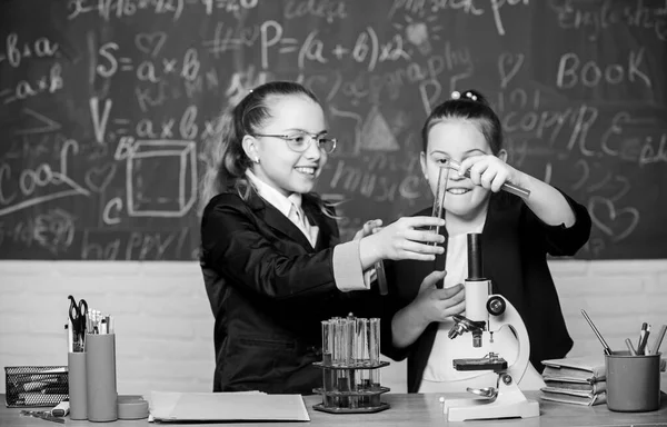 Εκπαιδευτικό πείραμα. Μικροσκόπιο και δοκιμαστικοί σωλήνες στο τραπέζι. Εκτελέστε χημικές αντιδράσεις. Βασικές γνώσεις χημείας. Οι συμμαθήτριες σπουδάζουν χημεία. Κάντε τη μελέτη της χημείας ενδιαφέρουσα — Φωτογραφία Αρχείου