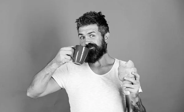 Croissant frais au four. Délicieux petit déjeuner. L'homme commence la matinée avec du café et croissant. Petit déjeuner malsain mais délicieux. Hipster barbu profiter du petit déjeuner boire du café. Concept de tradition du matin — Photo