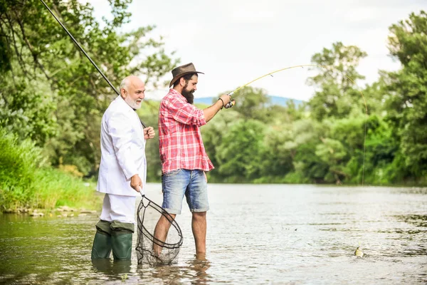Too busy. happy fishermen. Good profit. friends men with fishing rod and net. Fly fishing adventures. hobby of businessman. retirement fishery. retired dad and mature bearded son
