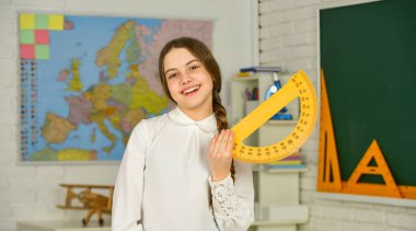 Kesinlikle bilim. Açıları derece cinsinden ölçün. Geometri dersi için okul ekstraktörü tutan küçük bir kız çocuğu. İletki kullanmayı öğreniyorum. Okula dönüyorum. Lise öğrencisi sınıfta geometri öğreniyor